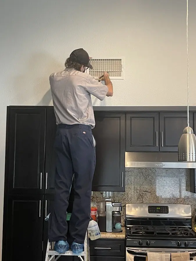 Technician inspecting an air vent during HVAC service in Deerfield Beach